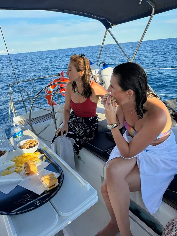 Couple enjoying sunset drinks on the bow of a sailing yacht with Tramuntana mountains behind